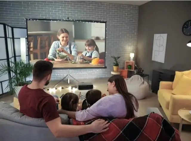 Rear view of a family on a couch watching home movies on a projector screen