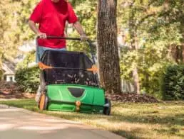 Man using a manual push lawn sweeper