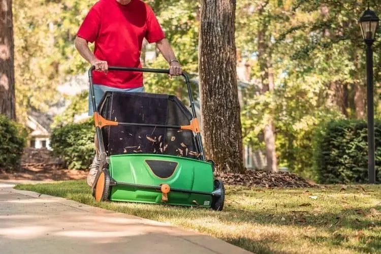 Man using a manual push lawn sweeper